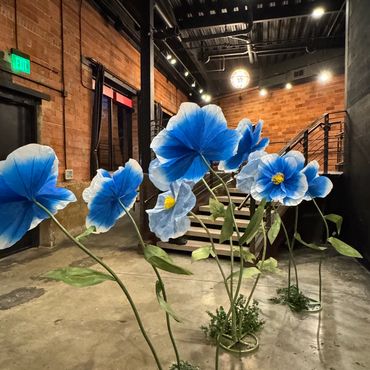 Large blue flower sculptures inside an industrial-style building.