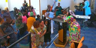 A lively church gathering with joyful attendees and a colorful speaker at the podium.