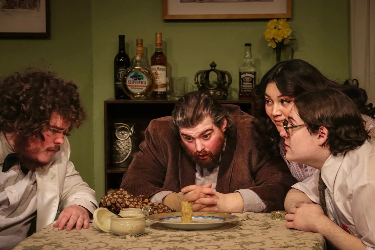 Four people intensely focused on a small stack of waffles at a table.