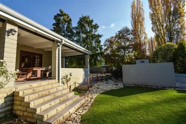 Backyard with stone steps, patio, and green lawn.