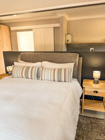 Cozy bedroom with a neatly made bed and bedside lamp.