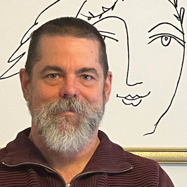 Man with a beard posing in front of a minimalist face drawing.