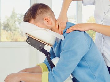 A man receiving a seated neck and shoulder massage.