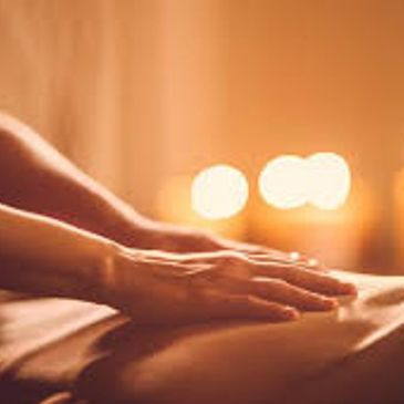 Hands gently resting on a massage table with warm candlelight in the background.