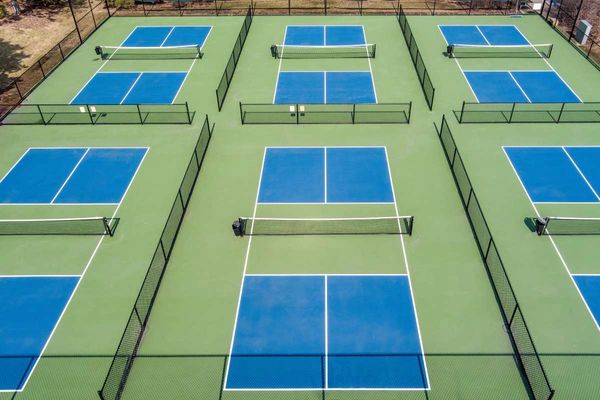 Aerial view of several blue and green tennis courts separated by fences.