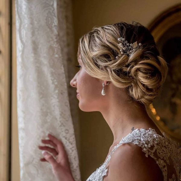 Bride in lace dress looking out a window.