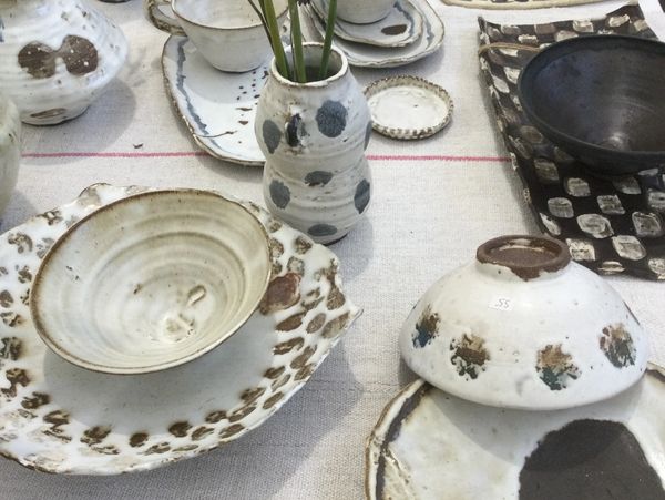 Handcrafted pottery pieces displayed on a cloth.