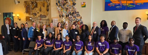 Group photo of diverse people in a room with artwork.