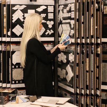Woman examining tile samples and color swatches in a showroom.