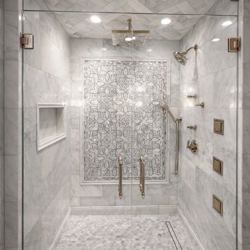 Luxurious marble shower with intricate tile design and gold fixtures.