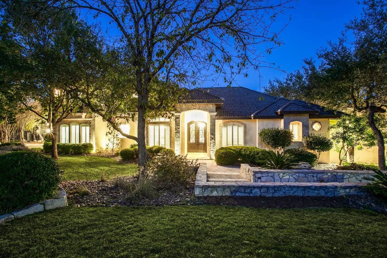 Illuminated house with lush garden at twilight.