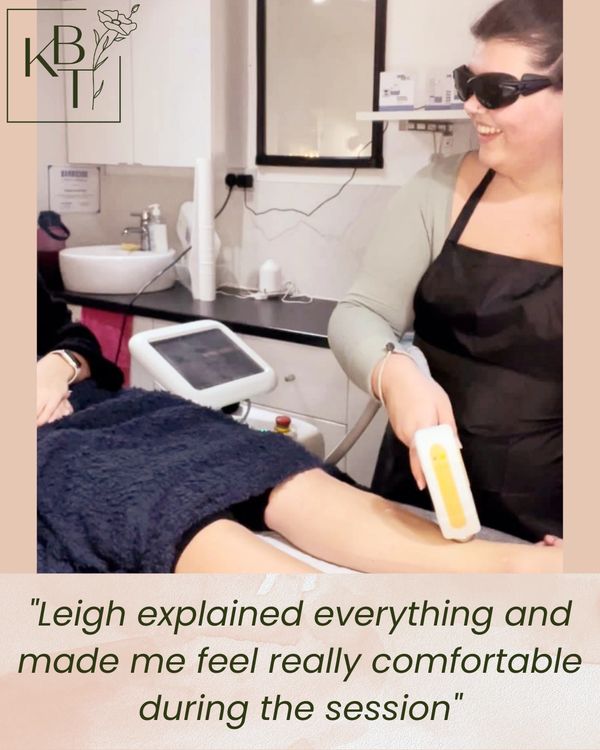 Smiling salon therapist doing laser hair removal on a client's legs