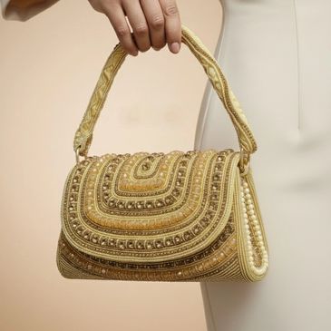 Tracky Trendz Luxurious handbag with intricate gold embroidery and beadwork, held by person in cream