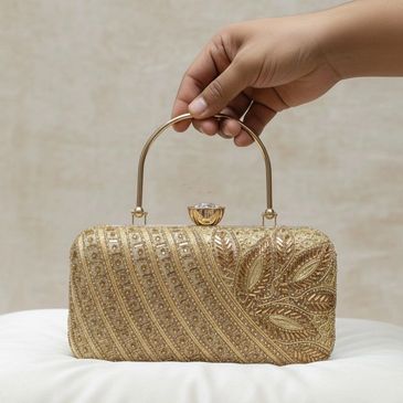 Tracky Trendz presents a golden embroidered clutch with leaf motifs, gemstone clasp, and luxe handle