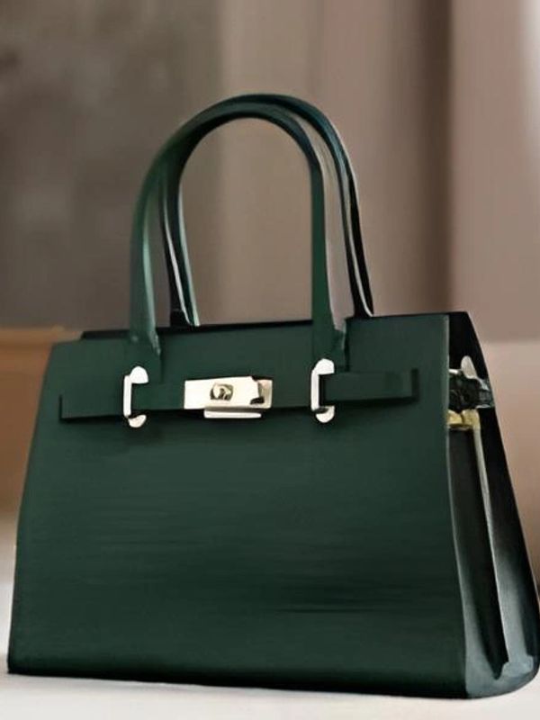 Elegant dark green handbag with gold hardware on a soft surface.