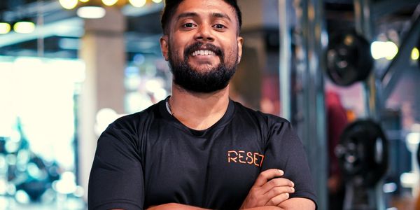 Man smiling confidently in a gym wearing a black RESET t-shirt.