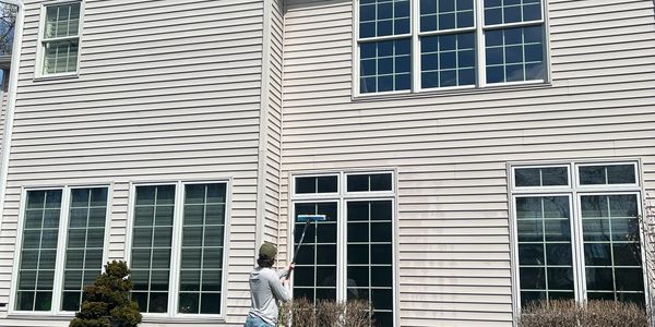 Window washer safely cleaning ground-floor residential exterior windows