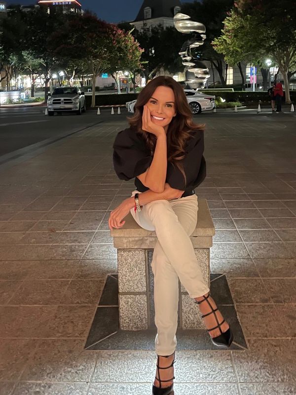 Woman sitting on a stone bench at night, smiling with relaxed posture.