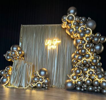 Elegant balloon decoration with gold backdrop and neon sign.