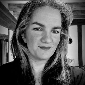 Black and white portrait of a woman with long hair smiling gently.