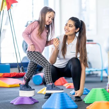 Pediatric physical therapist helping child improve balance mobility during home therapy Phoenix AZ