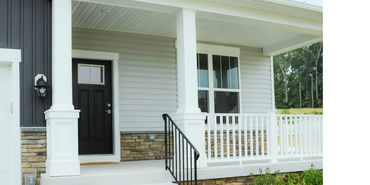 Modern house front porch with black door and white railings.