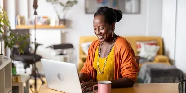 Smiling woman working on a laptop at a cozy home desk.