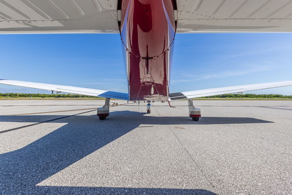 View from under a small airplane showing its tail and shadow on the runway.