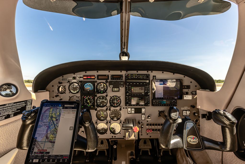 Cockpit of a Piper aircraft with flight instruments and navigation screens.