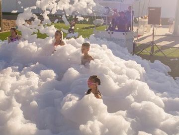 Children playing in a large foam pit outdoors.