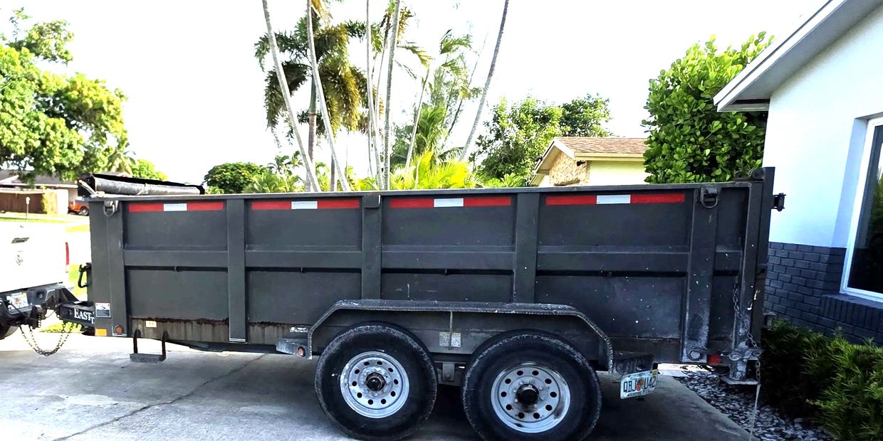 10 yard dumpster hitched to a white pickup truck in a driveway.