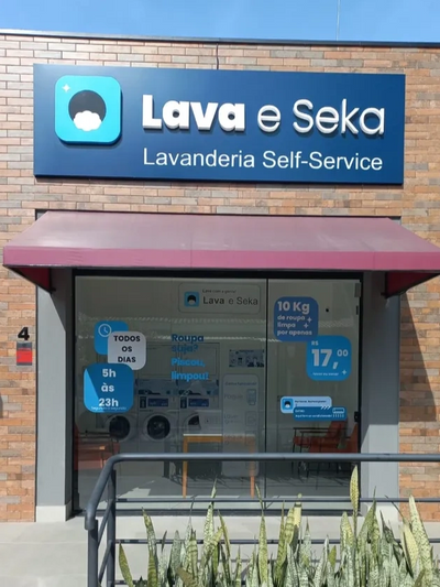 foto da fachada da lavanderia, com porta de vidro, parede de tijolos, placa fosca Lava e Seka.