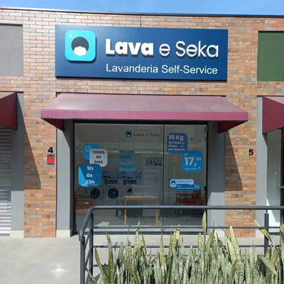 fachada da lavanderia, com vidros na frente, adesivo com preço e horário, placa em cima com o nome.