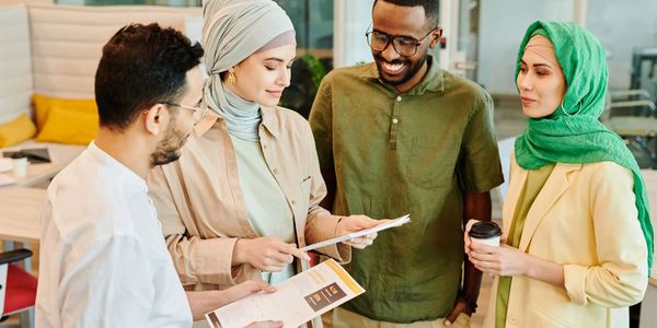 Four diverse colleagues reviewing documents together in a modern office.