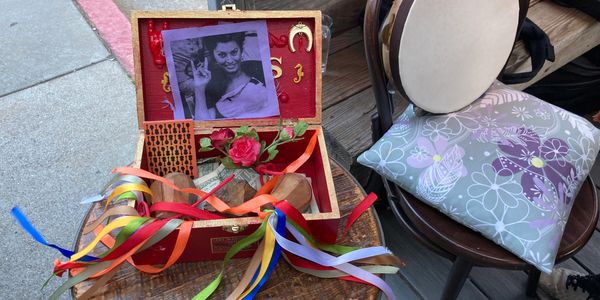 Open red box with photo, ribbons, and a rose inside.