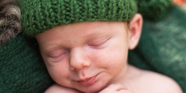 Newborn sleeping wearing a green hat