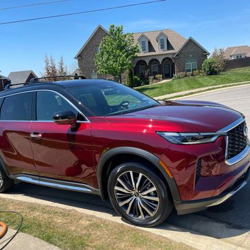 Shiny red SUV parked on a suburban street in front of a house.