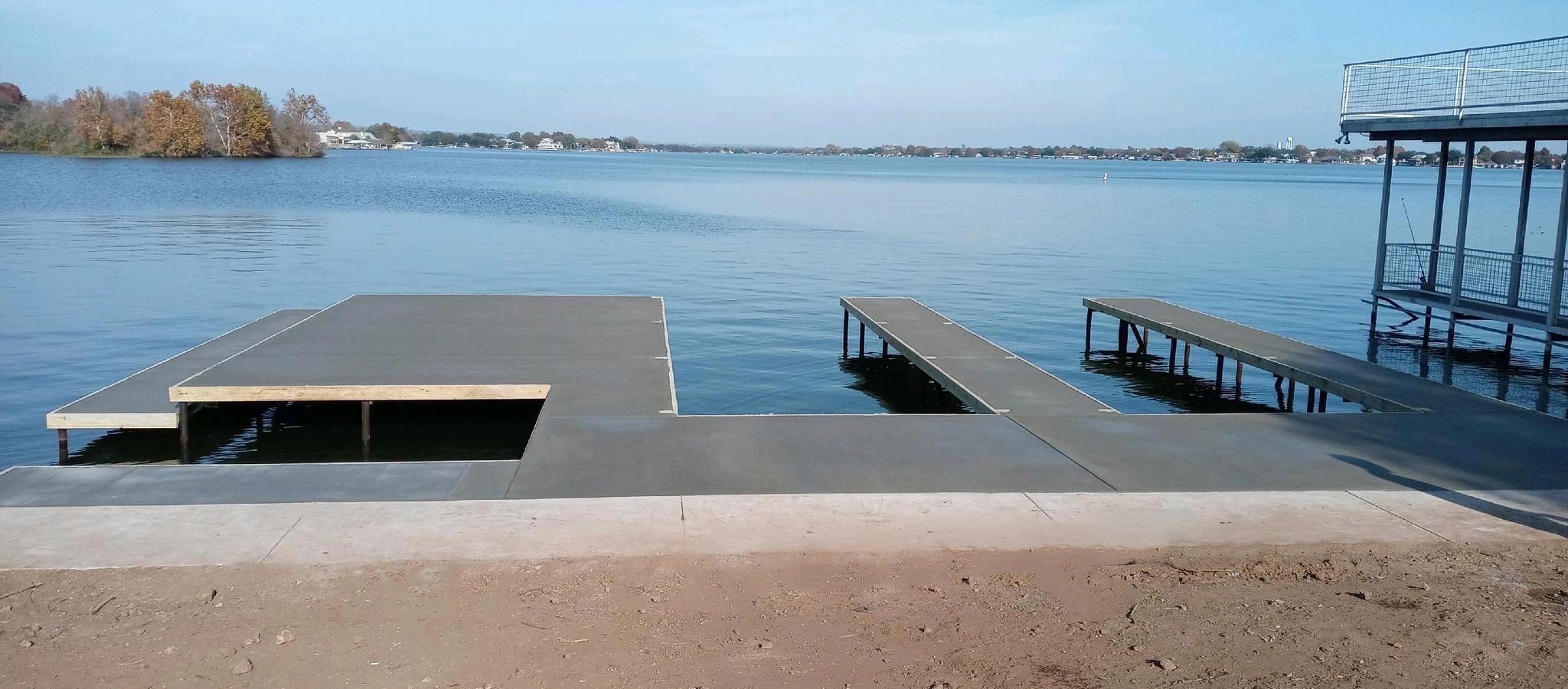 Concrete docks extending into a calm lake on a clear day.
