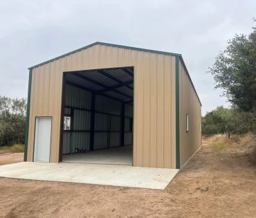 New metal building with open entrance on dirt terrain.