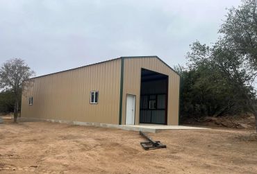 Large metal building in a rural area under a cloudy sky.