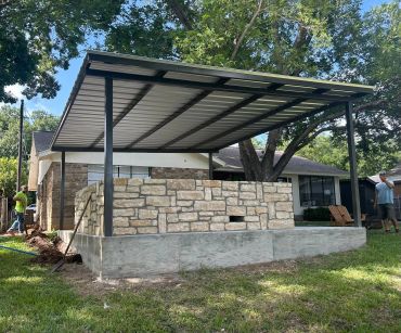 Stone outdoor structure with metal roof in a backyard.