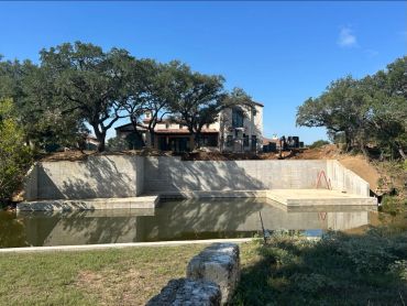 House on a hill behind a partially filled pond.