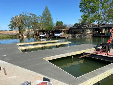 Newly constructed wooden dock over calm water on a sunny day.