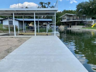 Concrete dock with a swing set by a calm lake.