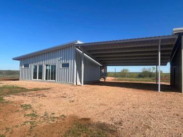 Modern metal building with carport on a gravel lot.