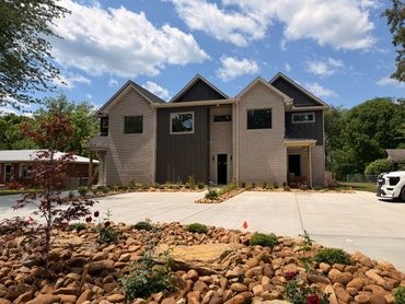 Modern two-story house with a spacious driveway and landscaped rock garden.