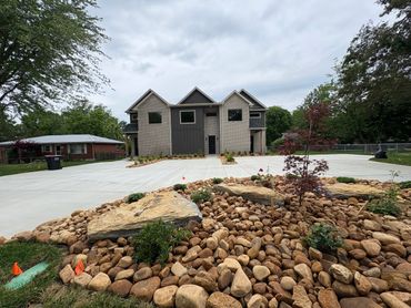 Modern two-story house with stone landscaping and spacious driveway.