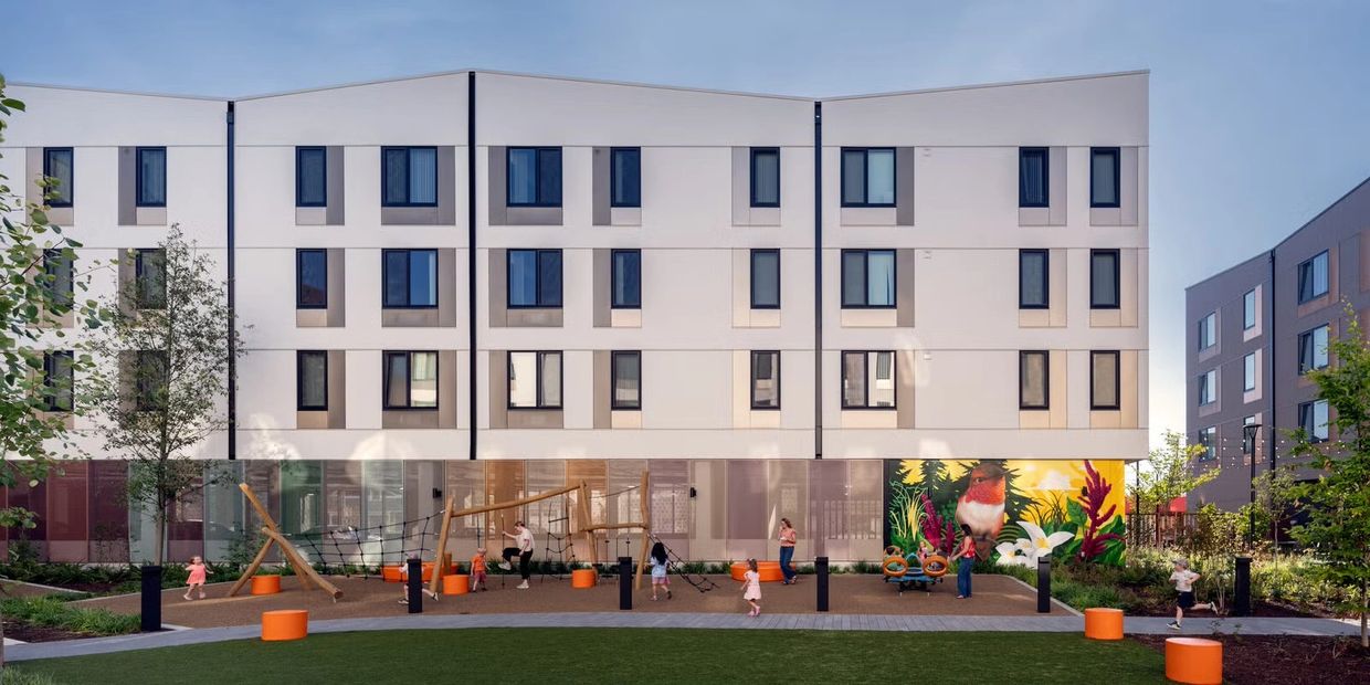 Modern apartment complex with a vibrant playground and mural.