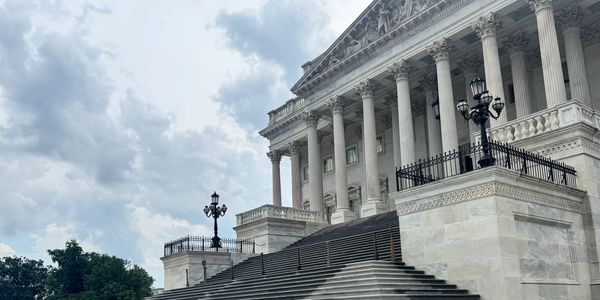 Grand neoclassical building with wide steps and columns under a cloudy sky.