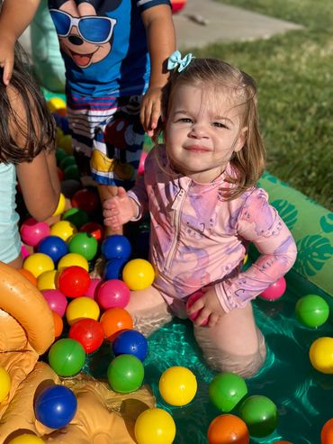 toddler girl in pool with plastic balls 